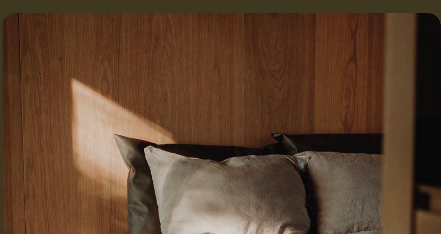 Interieur van een Eco by Nature lodge — houten wand en bed in warm licht