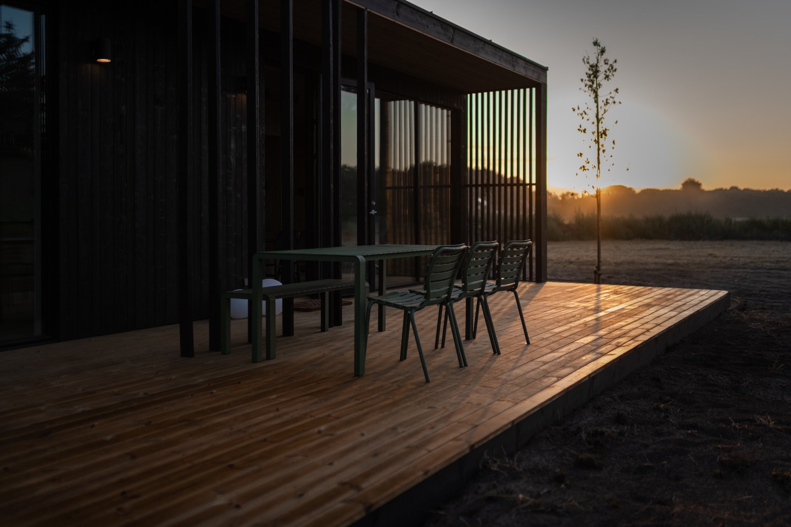 Het terras van De Stilte in het eerste licht, met de patio en de lamellen in de zonsopgang